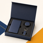 Open navy corporate gift box containing a slim portable power bank, round mobile phone grip and metal keychain arranged in a black fitted insert.