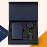 Open navy gift box containing a power bank, phone grip and matching metal keychain.