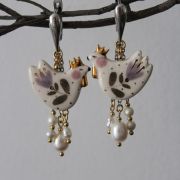 Pair of decorative bird-shaped drop earrings with gold crowns, floral details and dangling pearl beads.